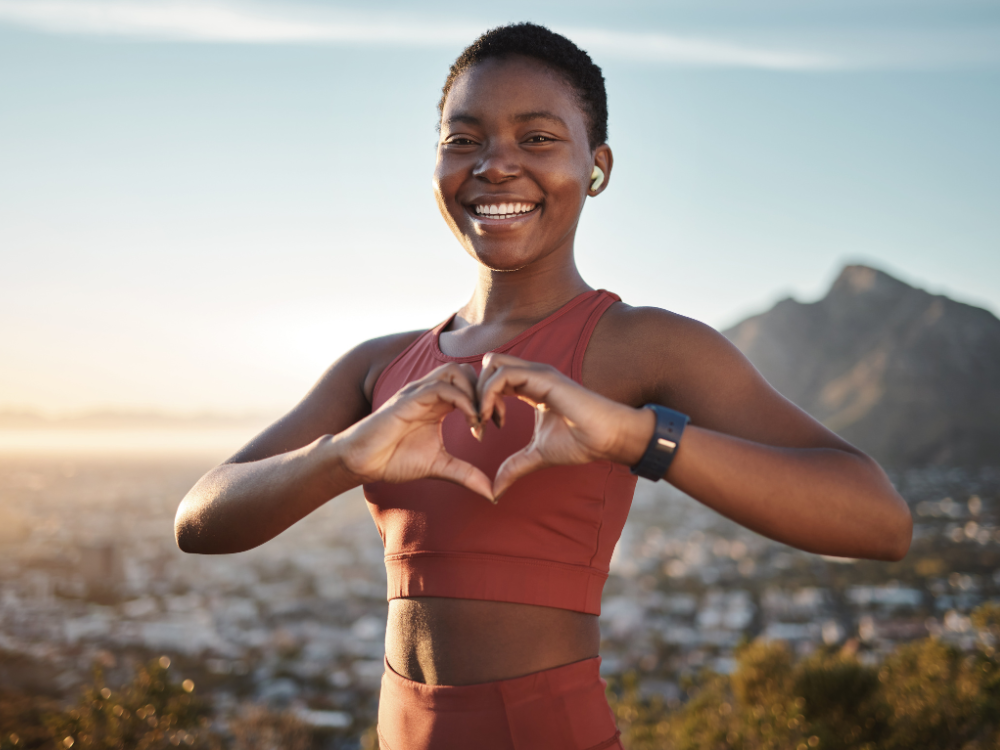 A woman holds her hands up making a heart sign