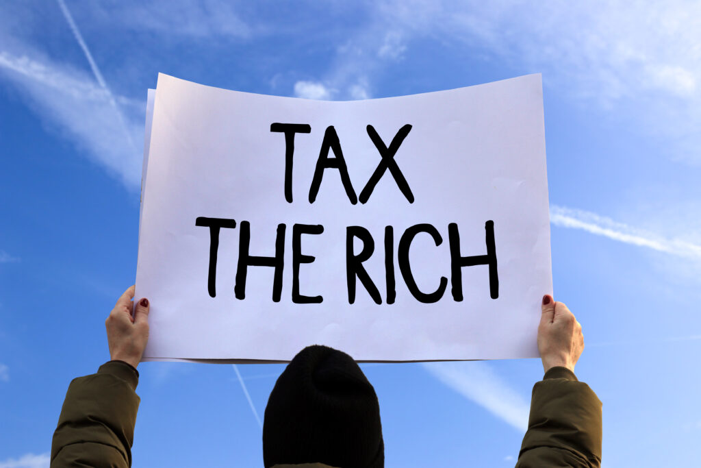 Photo of a protester with a sign that reads "Tax the rich"