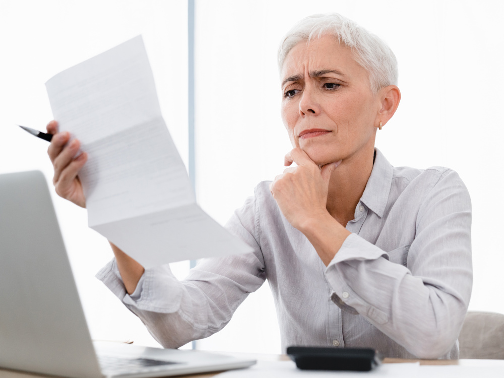 Photo of a businesswoman looking at a bill with an unhappy look on her face.
