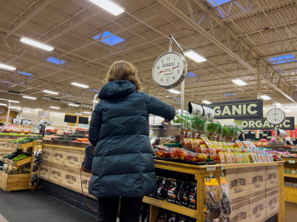 Image of a young Wisconsin woman grocery shopping, illustrating the forecast that Millennial and Gen Z spending will boost U.S. "necessity retail" like grocery