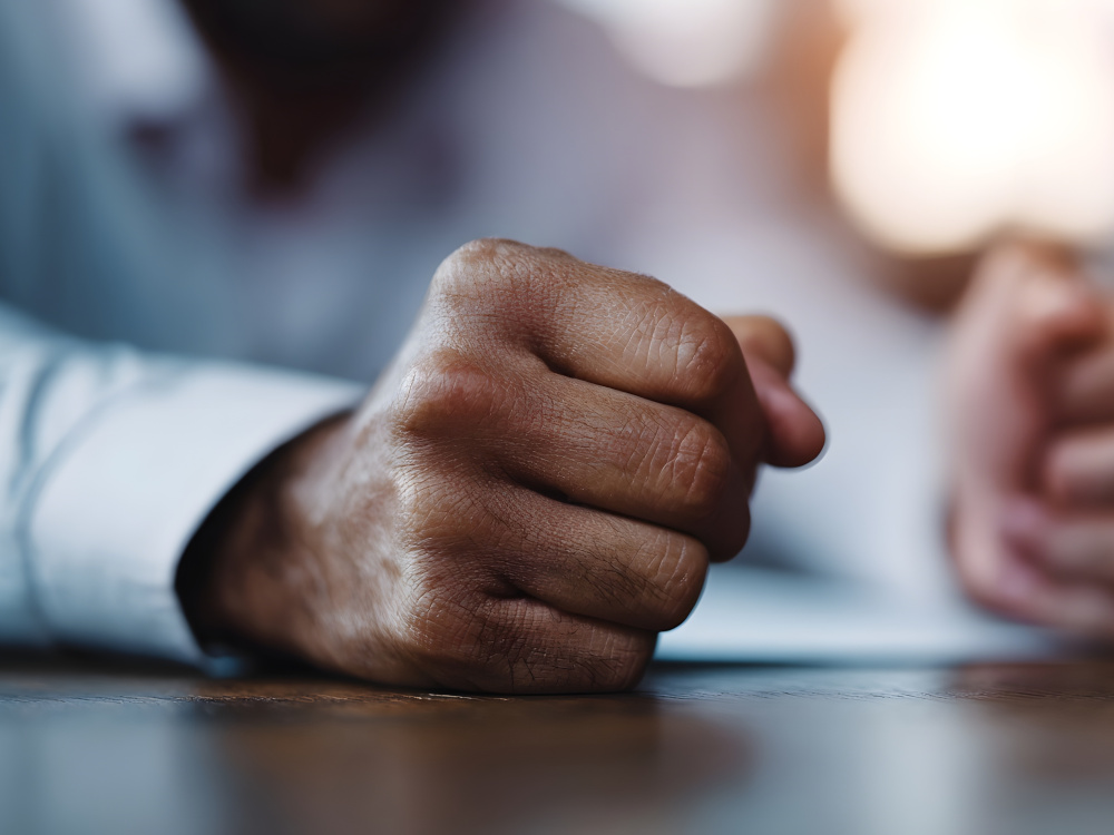 Illustration of a closed fist of the boss at his desk.