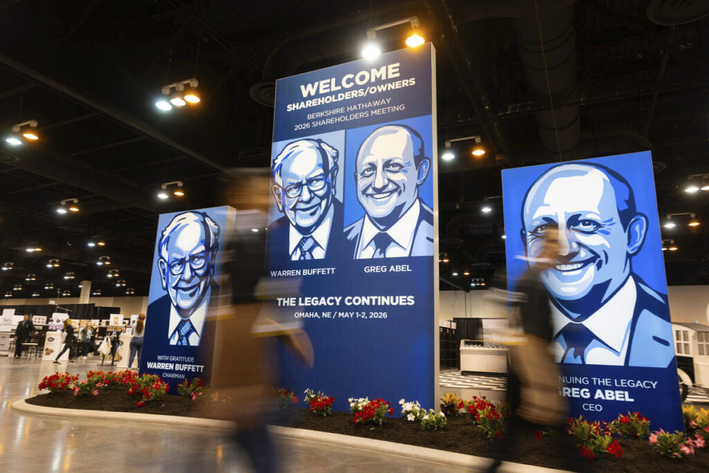 Photo from the 2026 Berkshire Hathaway annual meeting, showing a poster with images of Warren Buffett and new CEO Greg Abel. The picture illustrates the continuity of Berkshire Hathaway principles, which this article argues are applicable to family offices as well
