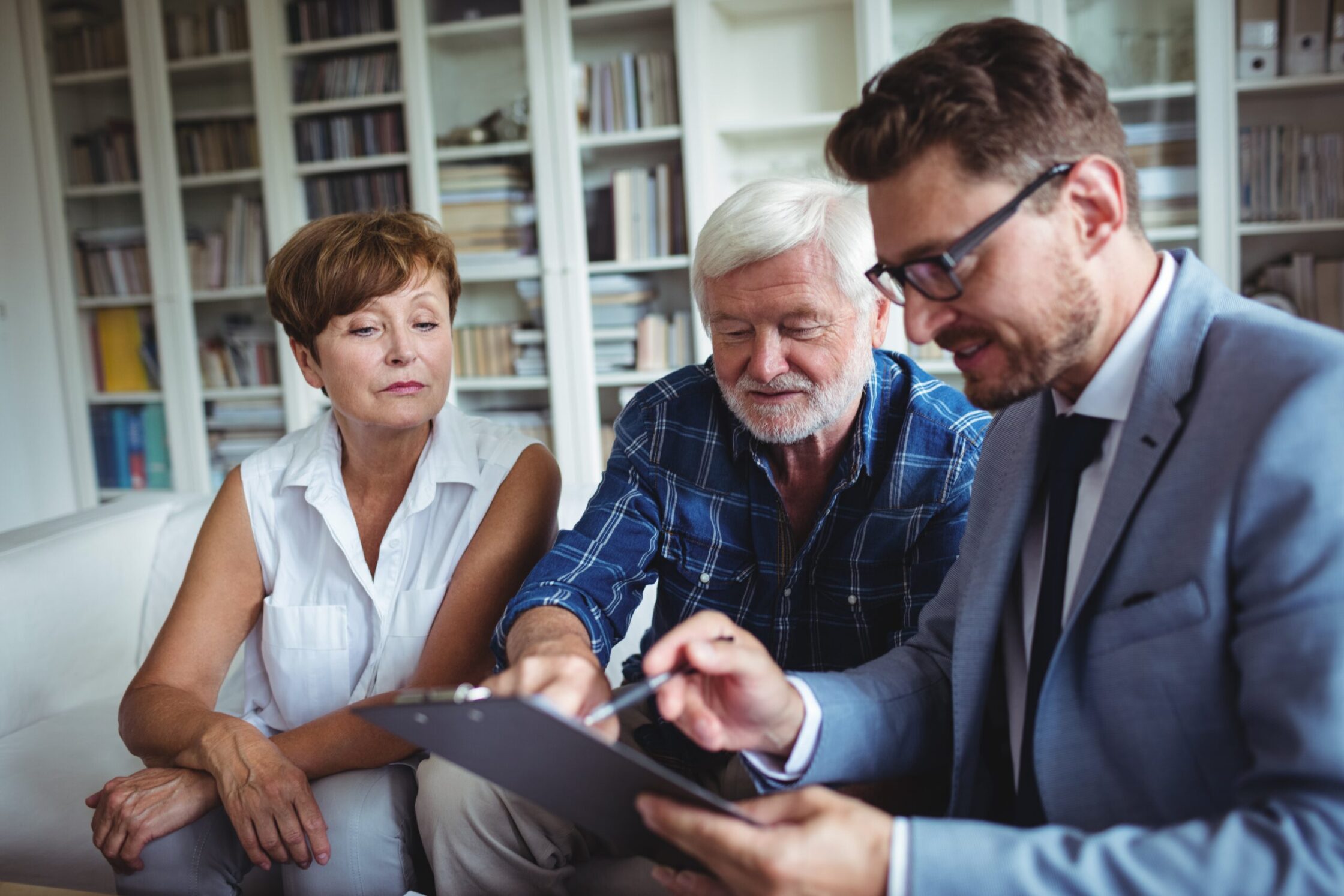 Photo of an elderly couple consulting an advisor about their estate, illustrating the importance of open communication about death and dying for family office advisors